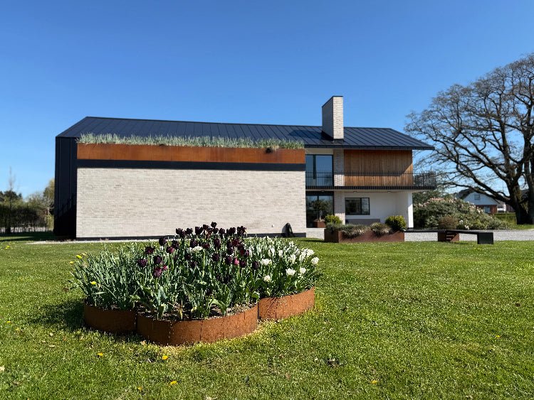 Flere bedringe i cortenstål i moderne have ved villa