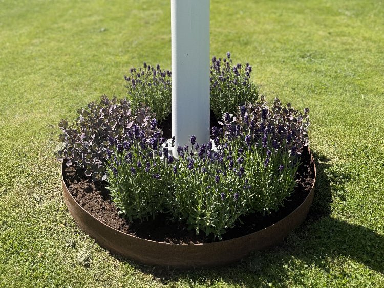 Rund bedring i cortenstål fra byJEMA på specialmål med lavendel omkring flagstang