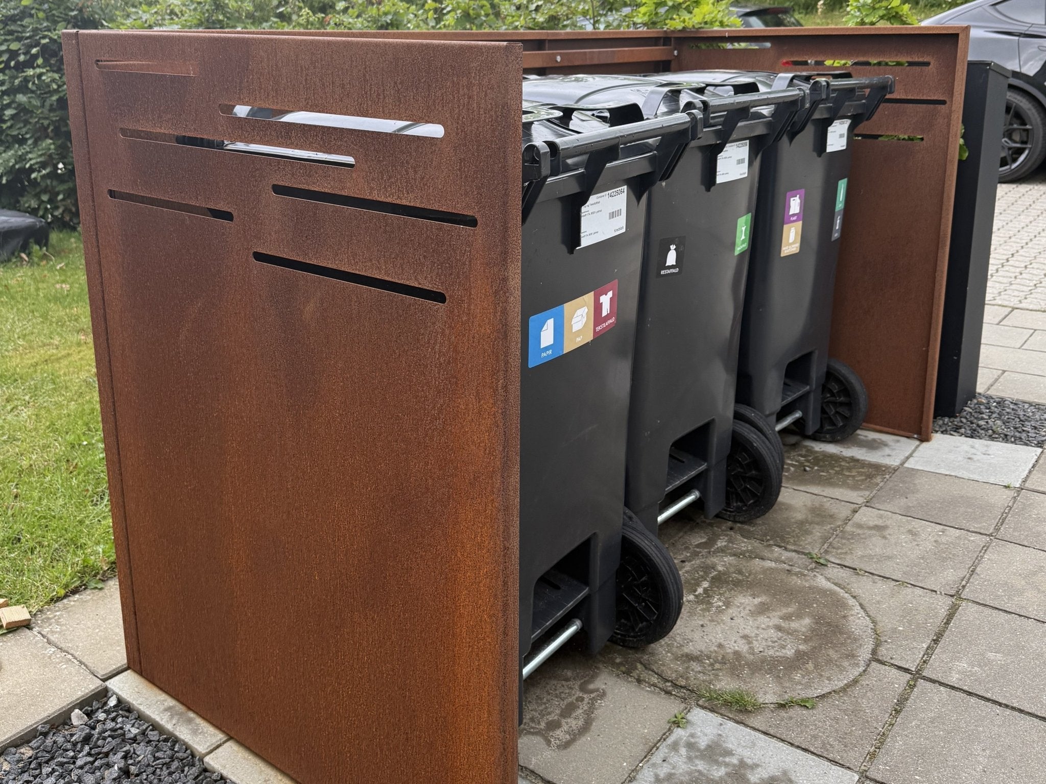 byJEMA skraldespandsskjuler i cortenstål med plads til tre affaldsbeholdere set fra siden