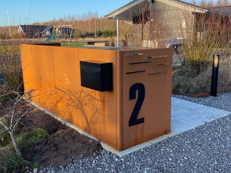 byJEMA skraldespandsskjuler i cortenstål med integreret husnummer og postkasse ved moderne bolig