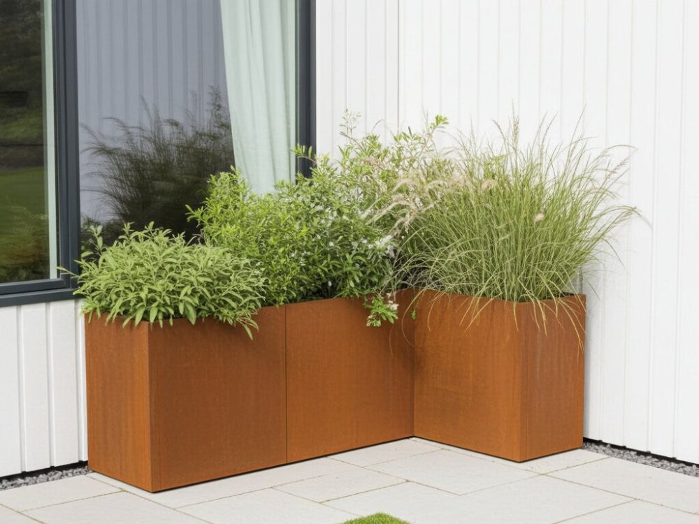 Hjørneopbygget plantekasse i cortenstål fra CUBY med grøn beplantning langs facade