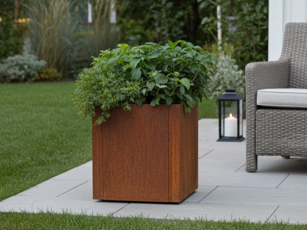 CUBY cortenstål plantekasse med frodige haveplanter i hyggeligt terrassehjørne