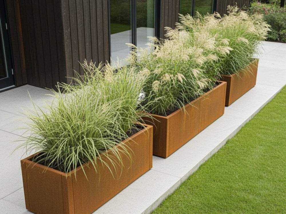 Flere CUBY plantekasser i cortenstål med prydgræs langs husfacade