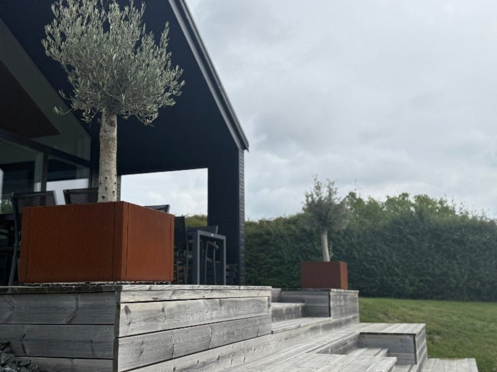 CUBY plantekasser i cortenstål placeret på træterrasse ved moderne hus