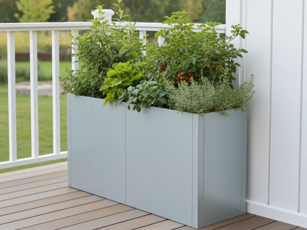 CUBY aflang plantekasse i galvaniseret stål med frodige planter placeret på terrasse ved rækværk