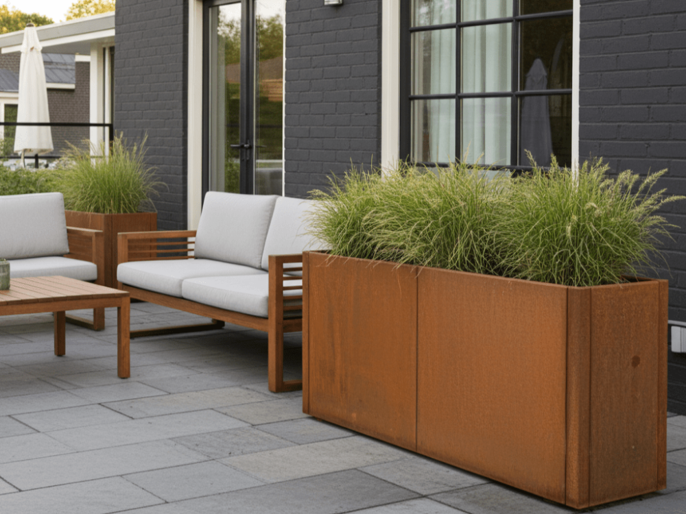 Rektangulær plantekasse i cortenstål fra CUBY med prydgræs foran moderne hus