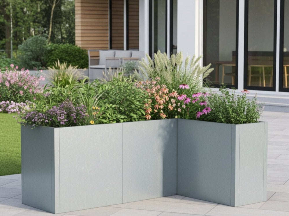 CUBY vinkel plantekasse i galvaniseret stål med blomstrende stauder ved terrasse