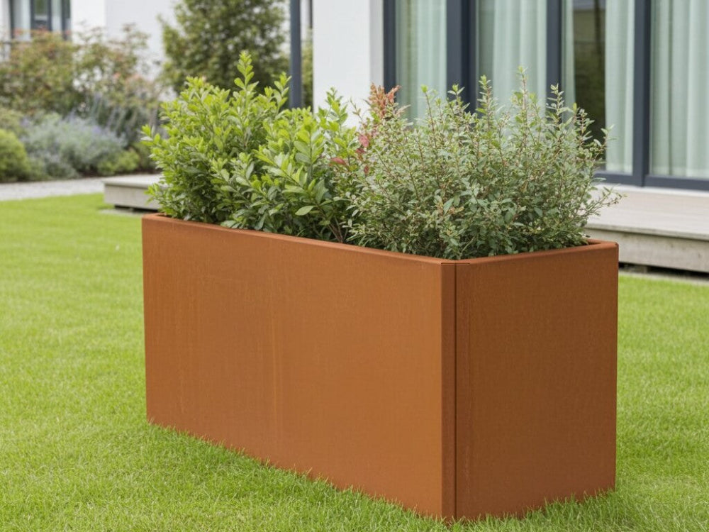 Aflang EDGY plantekasse i cortenstål med grøn beplantning på græsplæne