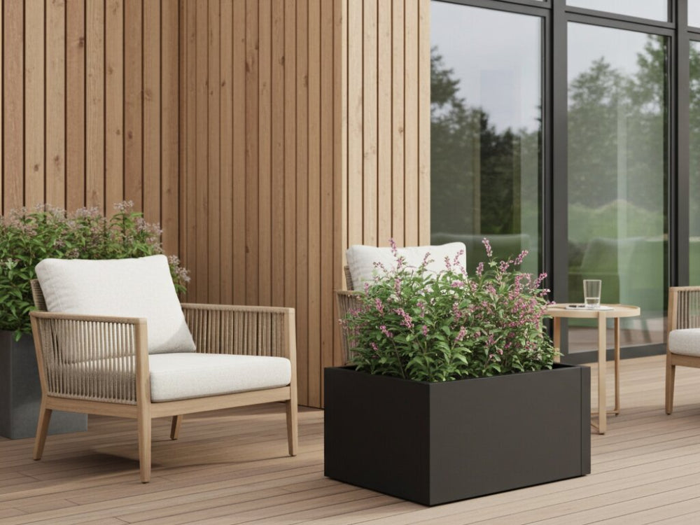 Lavt højbed i sort stål med blomstrende stauder ved siddeområde