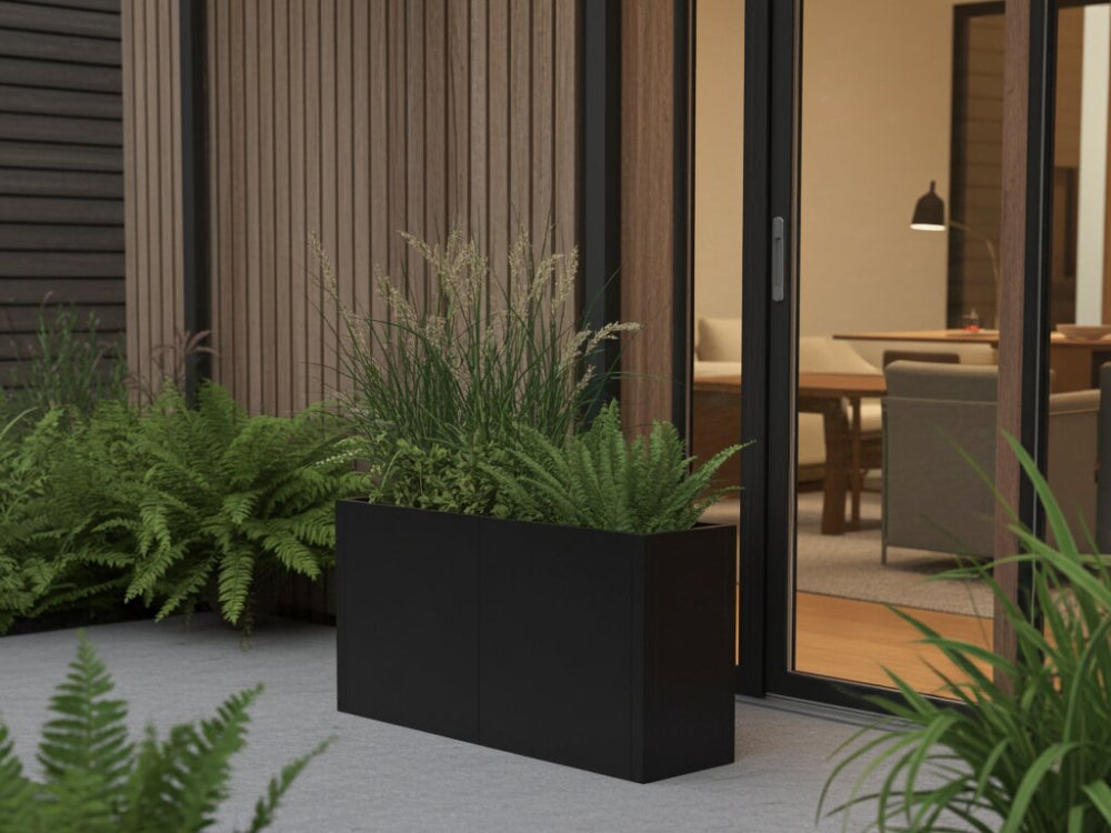 Minimalistisk plantekasse i sort stål med bregner ved husets indgang