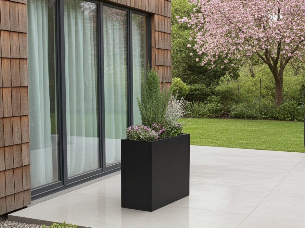 Minimalistisk plantekasse i sortlakeret stål foran moderne bolig