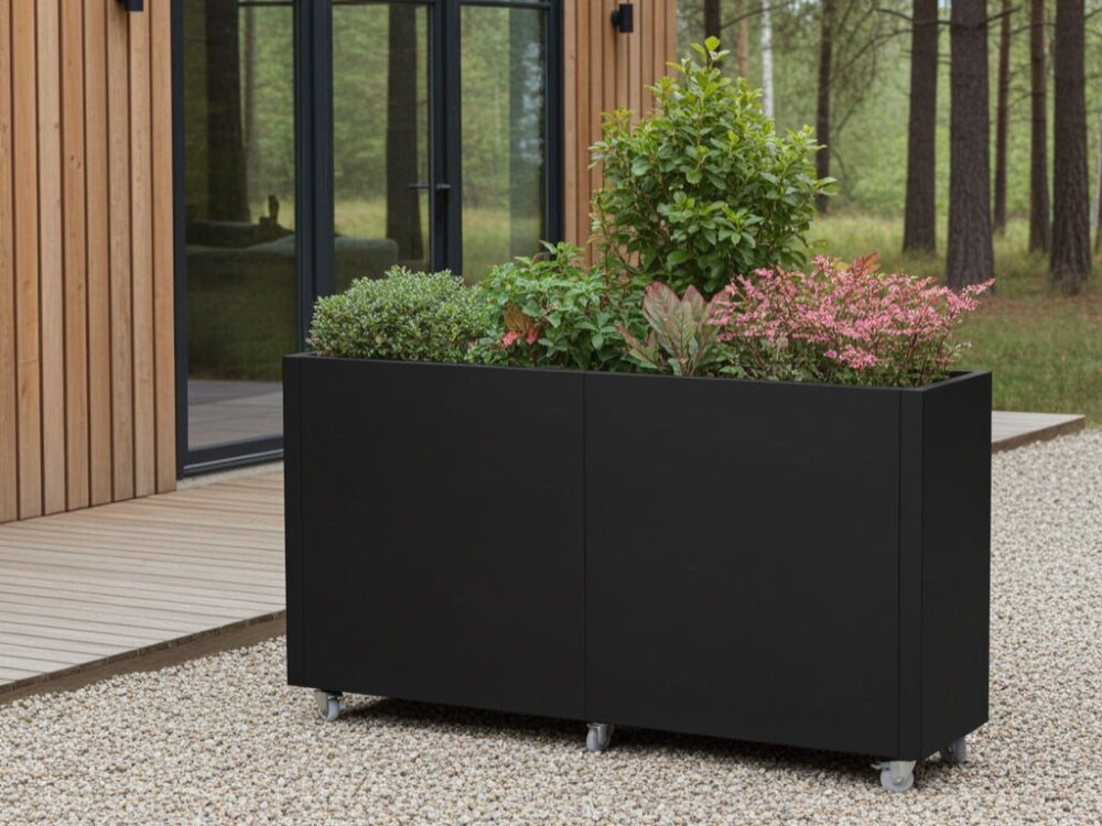 Sort plantekasse på hjul med buske og blomstrende planter i haven