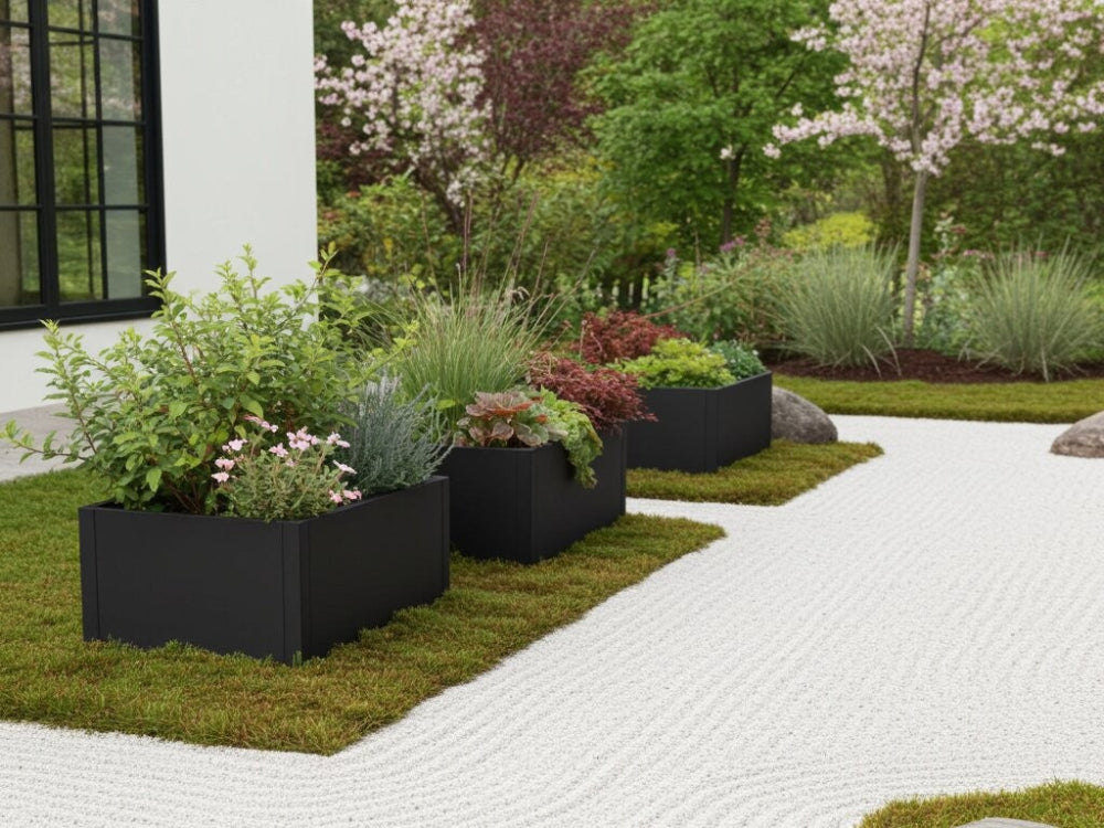 Sorte plantekasser i stål med stauder og prydgræsser langs havesti i moderne have
