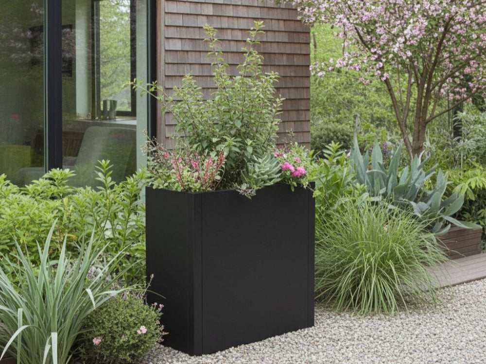 Sort plantekasse i stål med grønne planter i frodig have