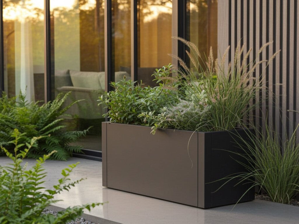 Sort plantekasse i stål med prydgræsser og grøn beplantning ved moderne terrasse