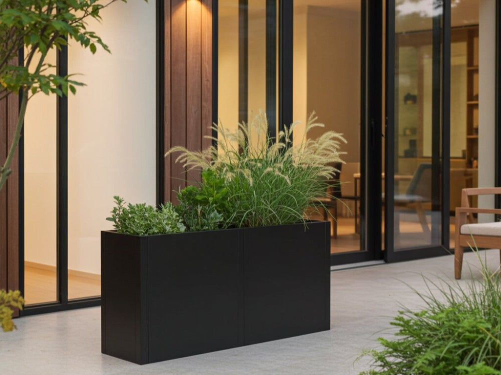 Sort plantekasse i stål med prydgræsser ved moderne terrasse
