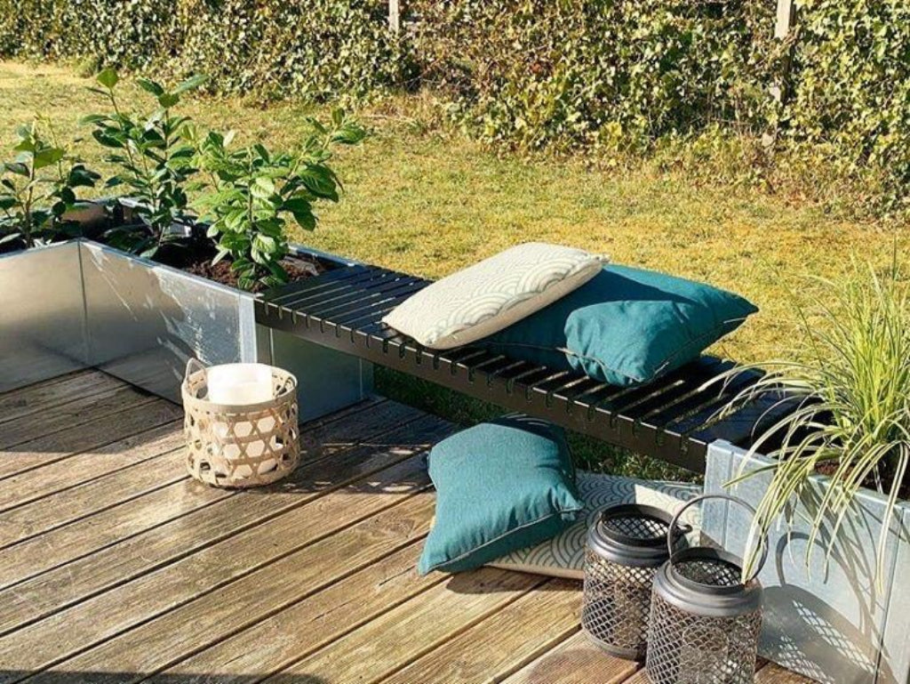 Vinkel plantekasse i galvaniseret stål med sort bænk på træterrasse