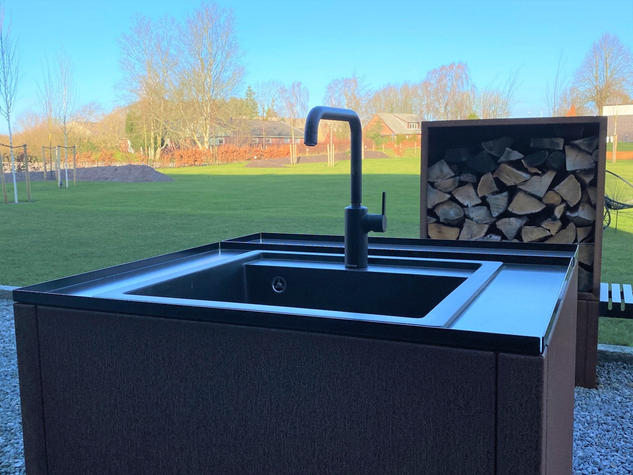 Nærbillede af integreret vask i cortenstål udekøkken modul med sort armatur