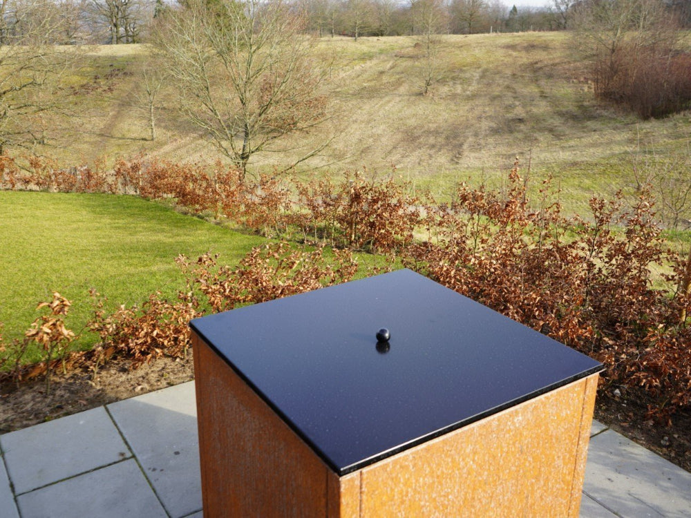 Bålgrill med låg i sort stål i udendørs omgivelser