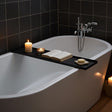 Sortlakeret badekarhylde i stål på tværs af badekar med bog og stearinlys i spa-inspireret badeværelse