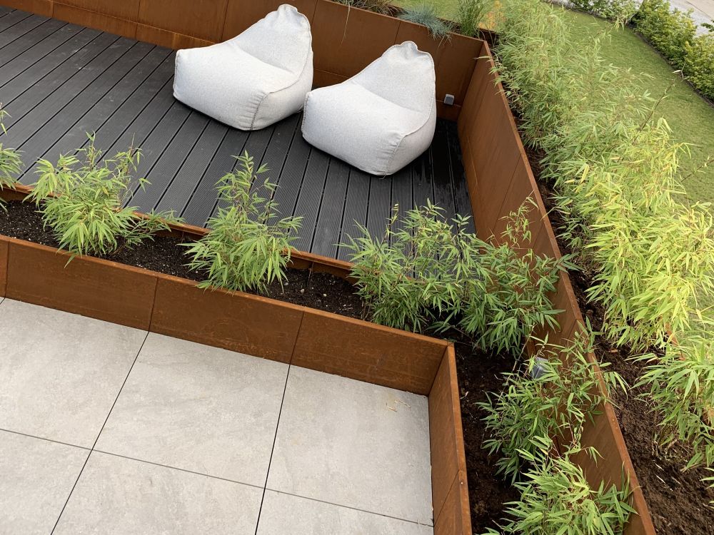 byJEMA plantekasser i cortenstål integreret i terrasse med siddeområde