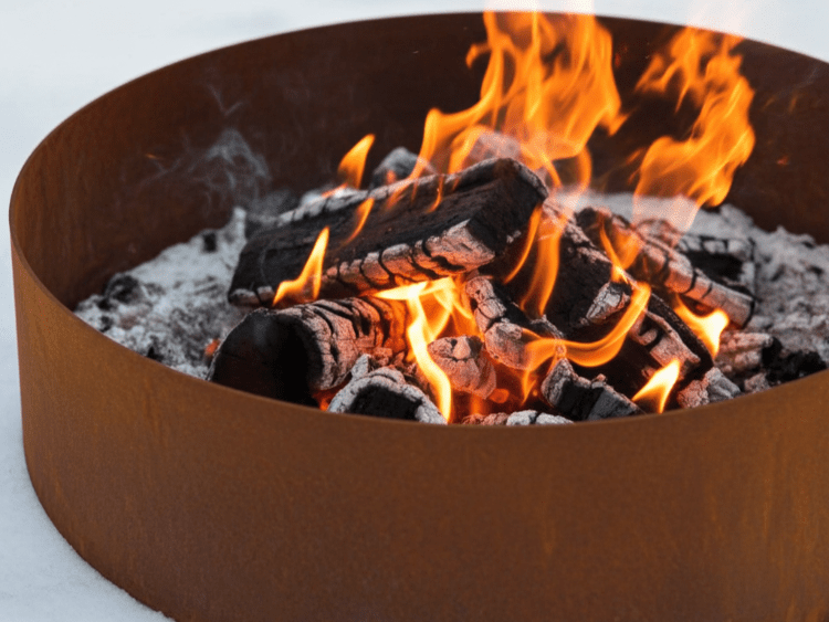 Detaljebillede af bålkar i cortenstål med glødende brænde og flammer