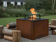 CUBY bålgrill i cortenstål med levende flammer i grøn naturhave