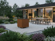 CUBY bålgrill i cortenstål placeret i moderne have med arkitektur, terrasse og spiseområde