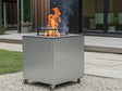 CUBY bålgrill i galvaniseret stål på terrasse ved hus med grøn beplantning og synlige flammer