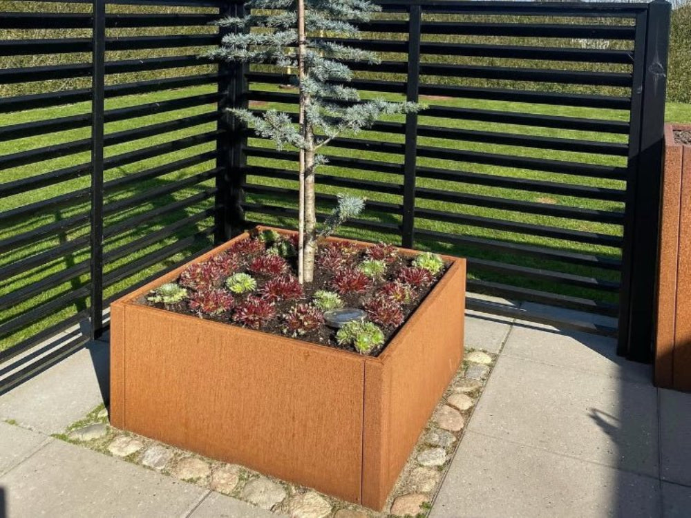 Cortenstål plantekasse fra CUBY med lille nåletræ og stenbed ved terrasse