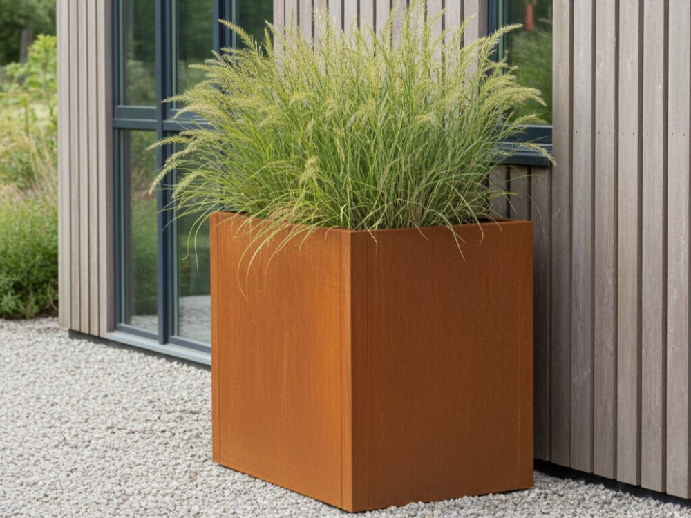 CUBY plantekasse i cortenstål med højt prydgræs ved moderne husfacade
