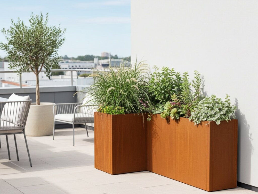 Vinkelopstillet CUBY plantekasse i cortenstål med prydgræs og blomster på lys tagterrasse