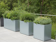 Flere CUBY plantekasser i galvaniseret stål med prydgræs og urter ved terrasse