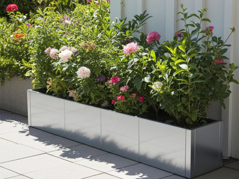 Lang plantekasse i galvaniseret stål fra CUBY med blomstrende planter ved terrasse
