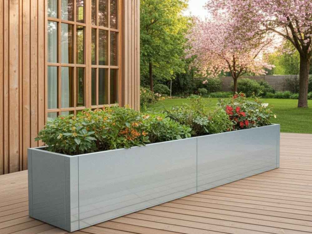 CUBY plantekasse i galvaniseret stål med blomstrende planter ved terrasse