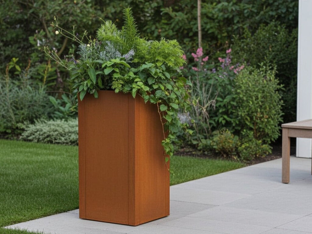 Høj CUBY plantekasse i cortenstål med grønne planter i haven