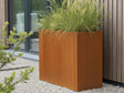 Høj CUBY plantekasse i cortenstål med prydgræs ved moderne træfacade
