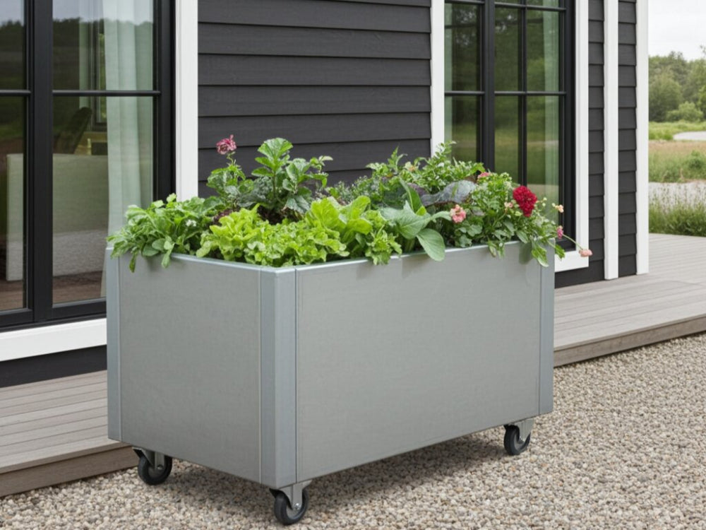 Højbed i galvaniseret stål på hjul med bladgrønt og urter ved terrasse
