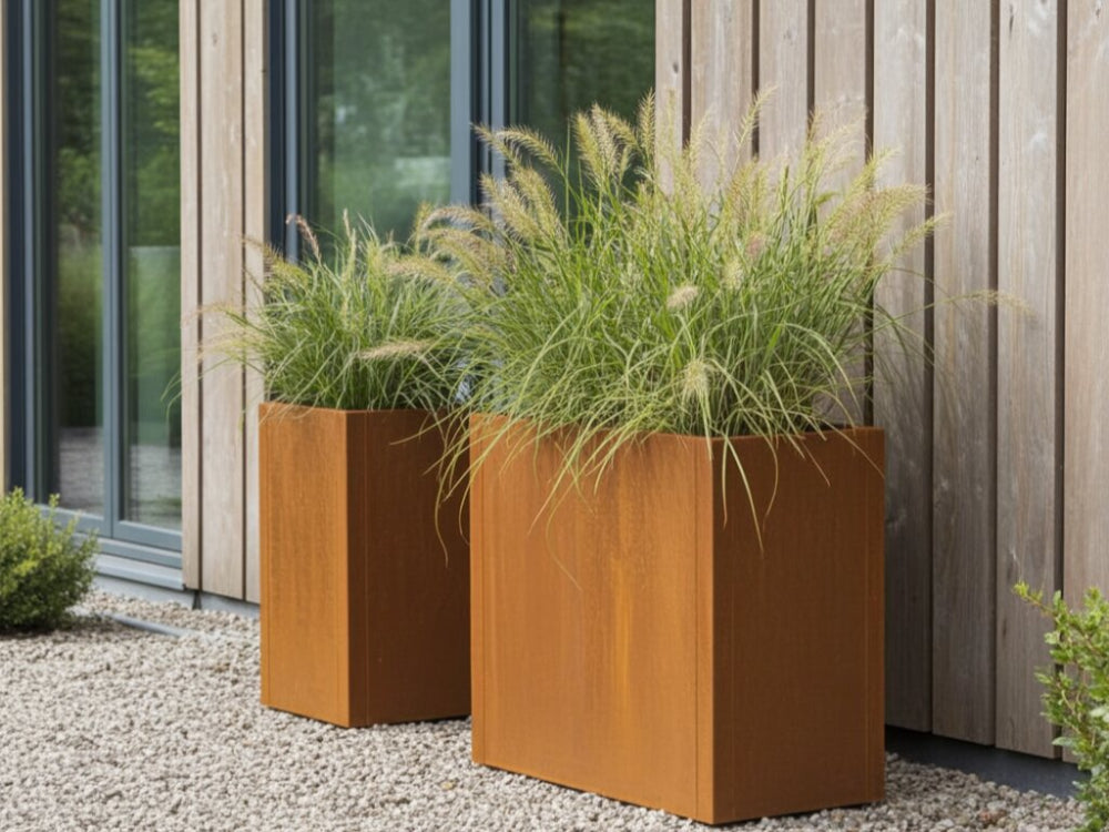 To CUBY plantekasser i cortenstål med prydgræs ved husets facade