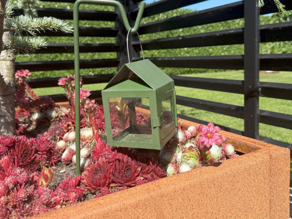 CUBY plantekasse i cortenstål med røde sedumplanter og grøn lanterne i bed
