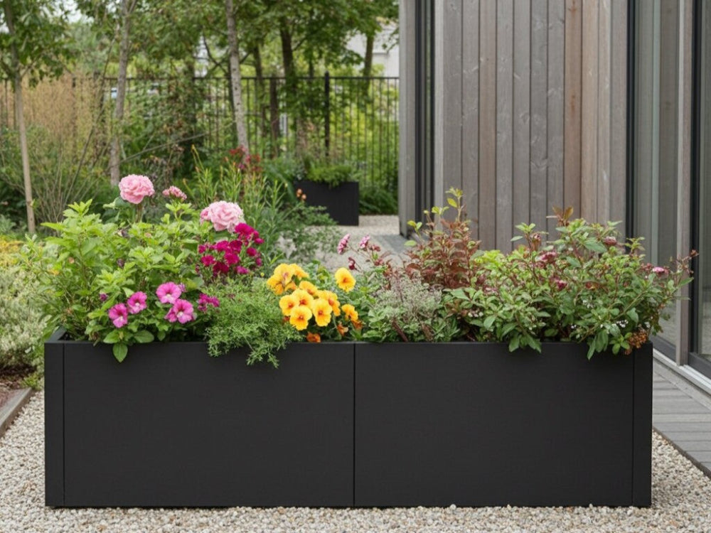 Lang sort plantekasse i stål med blomstrende planter i moderne have