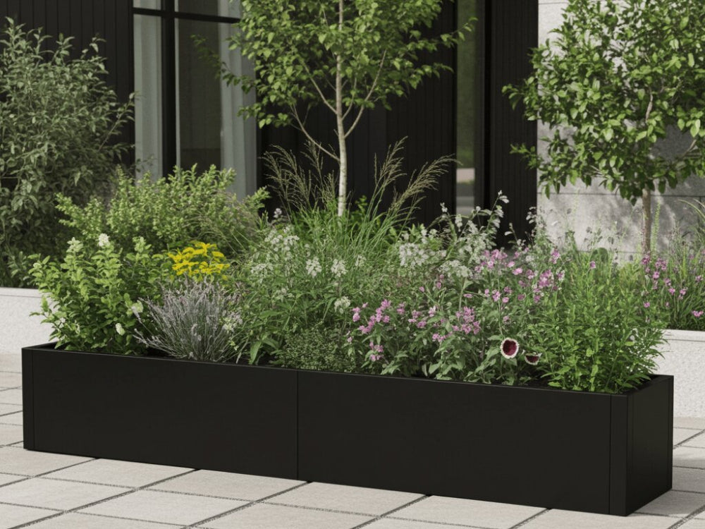 Sort plantekasse i stål med stauder og prydgræsser i moderne gårdrum
