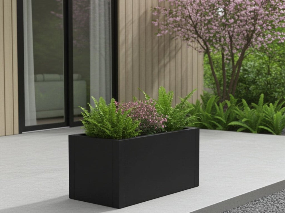 Sort plantekasse i stål med bregner og blomstrende planter ved husfacade