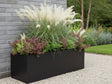 Sort plantekasse i stål med prydgræsser og stauder i moderne grusbed