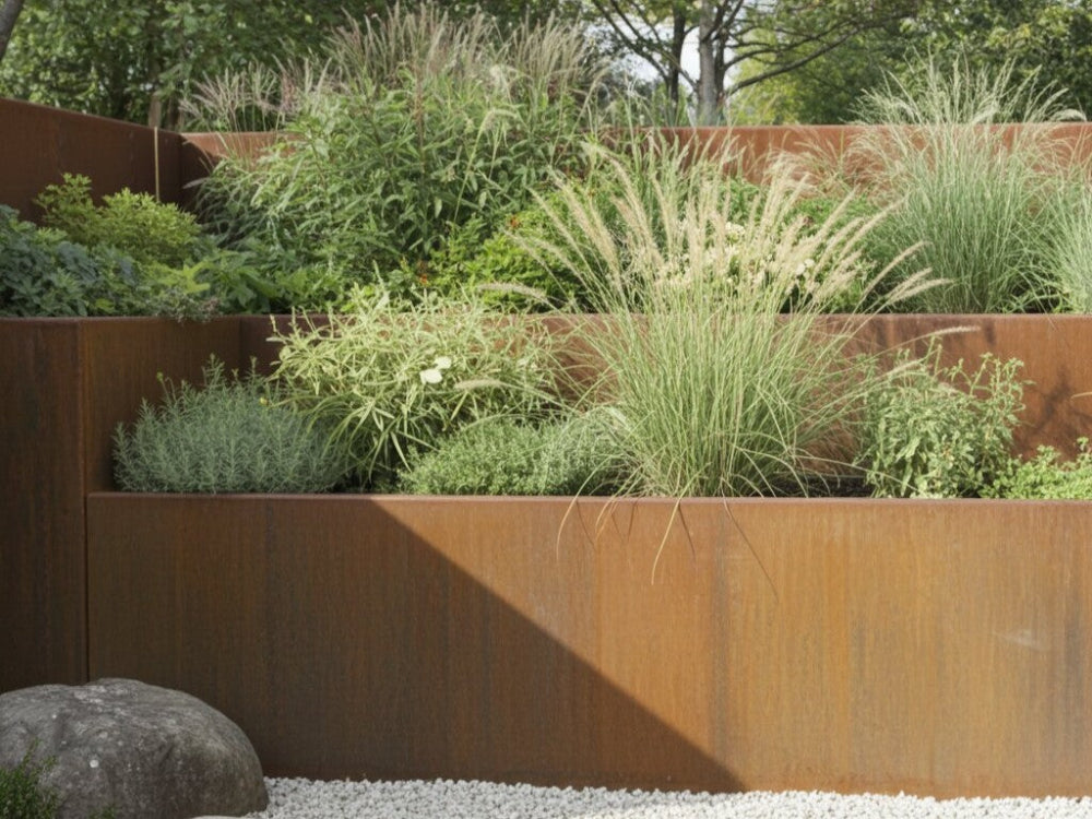 Støttemur i cortenstål med prydgræsser og stauder i terrasseret havebed