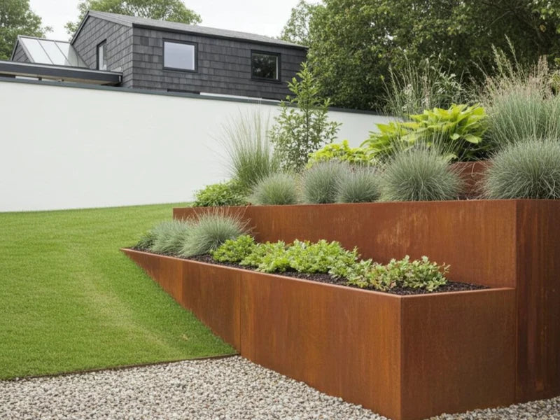 Terrasseret støttemur i cortenstål med prydgræsser og planter i have