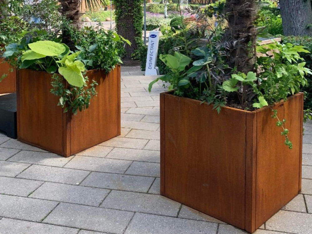CUBY plantekasser i cortenstål med frodig beplantning på belagt byplads