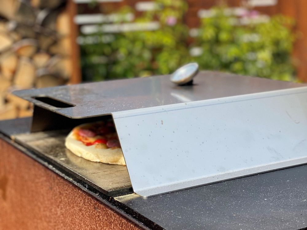 Pizzaovn i rustfrit stål placeret på grillplade